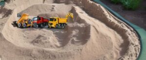 Eine Sammlung von Spielzeug-Trucks in einem Sandkasten mit den besten RC-LKW-Optionen für Kinder.
