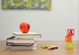 Ein Stapel Bücher und ein Apfel auf einem Tisch.