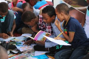 Eine Gruppe Kinder sitzt auf dem Boden und liest Bücher.