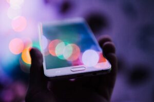 Eine Person hält ein Smartphone mit Bokeh-Lichtern hoch.