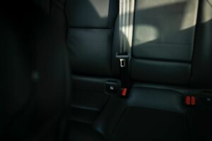 Der Innenraum eines Autos mit schwarzen Sitzen und roten Gurten.