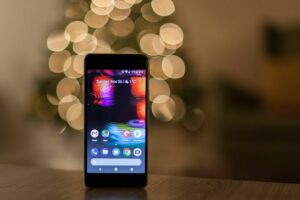 Ein Smartphone liegt auf einem Tisch vor einem Weihnachtsbaum.